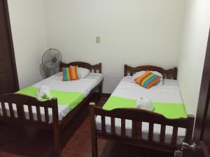two twin beds in a room with a fan at Hostal El Jardin in León