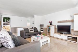 Una sala de estar con un sofá y un televisor. en Villa Grace by Villa Plus, en Es Mercadal
