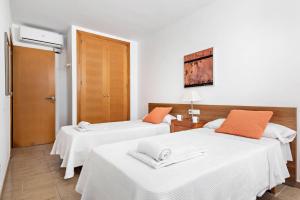 2 camas en una habitación con sábanas blancas y almohadas de color naranja en Villa Grace by Villa Plus, en Es Mercadal 17 fotos más