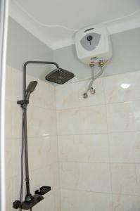 a shower with a shower head on the wall at Big Thrills Hotel and Suites Kampala in Kampala