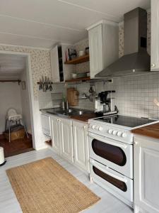 a kitchen with white cabinets and a stove top oven at Solröje in Simrishamn