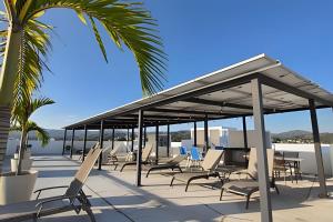 un pabellón con sillas y palmeras en una playa en Costa Paraíso Estudio D-21, en Bucerías