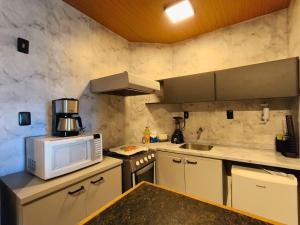 une cuisine avec un micro-ondes et une cuisinière four supérieur dans l'établissement Lindo APT Vista Mar Completo com Piscina no Rooftop do EDF, Próximo ao Porto da Barra, à Salvador