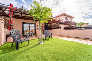 a yard with two chairs and a palm tree at Villa Colibri Azul in Lajares