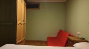 a bedroom with a red chair and a bed at SIERRA NEVADA Acogedor 2 habitaciones y bien ubicado Edifico Europa in Sierra Nevada