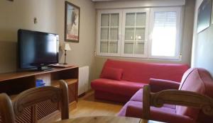 a living room with a red couch and a tv at SIERRA NEVADA Acogedor 2 habitaciones y bien ubicado Edifico Europa in Sierra Nevada