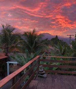 ペルイベにあるPousada Recanto dos Pássarosの椰子の木と柵のあるデッキの上の夕日 +43枚の写真