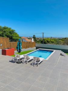 una piscina con 2 tumbonas y una sombrilla en Comfort Home Guest House, en East London