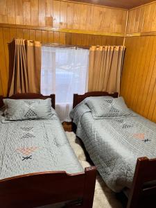 two beds in a room with a window at Cabaña frente al mar en Carretera Austral in Puerto Montt