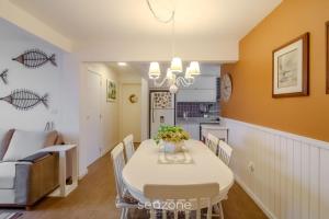 a dining room and kitchen with a white table and chairs at Apto 3Q quadra mar c/ Garagem em Piçarras NRA0490 in Piçarras