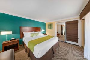 a hotel room with a large bed and a sliding glass door at Best Western Harbour Inn & Suites Huntington - Sunset Beach in Huntington Beach