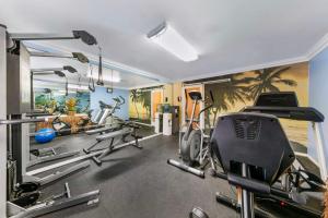 a gym with exercise equipment in a room with palm trees at Best Western Harbour Inn & Suites Huntington - Sunset Beach in Huntington Beach