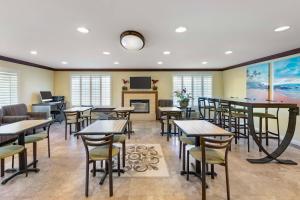 a dining room with tables and chairs and a fireplace at Best Western Harbour Inn & Suites Huntington - Sunset Beach in Huntington Beach