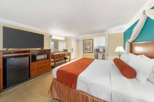 a hotel room with a large bed and a flat screen tv at Best Western Harbour Inn & Suites Huntington - Sunset Beach in Huntington Beach