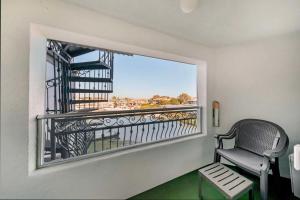 a room with a balcony with a chair and a window at Best Western Harbour Inn & Suites Huntington - Sunset Beach in Huntington Beach