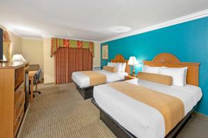 a hotel room with two beds and a television at Best Western Harbour Inn & Suites Huntington - Sunset Beach in Huntington Beach