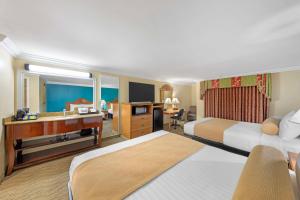 a hotel room with two beds and a desk at Best Western Harbour Inn & Suites Huntington - Sunset Beach in Huntington Beach