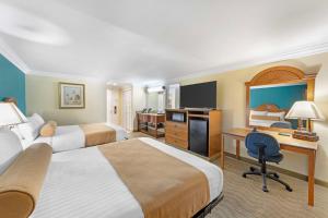 a hotel room with two beds and a desk at Best Western Harbour Inn & Suites Huntington - Sunset Beach in Huntington Beach