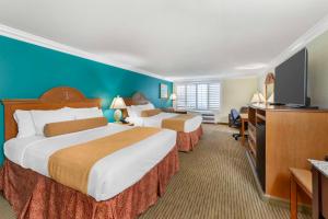 a hotel room with two beds and a flat screen tv at Best Western Harbour Inn & Suites Huntington - Sunset Beach in Huntington Beach