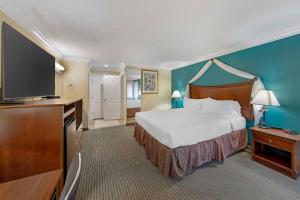 a hotel room with a bed and a flat screen tv at Best Western Harbour Inn & Suites Huntington - Sunset Beach in Huntington Beach