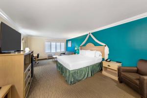 a hotel room with a bed and a flat screen tv at Best Western Harbour Inn & Suites Huntington - Sunset Beach in Huntington Beach