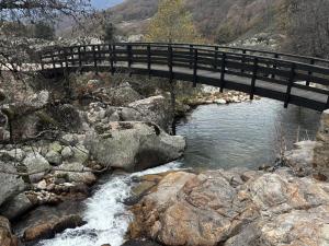 a black bridge over a river with rocks at El caserío de la abuela in Cabezuela del Valle