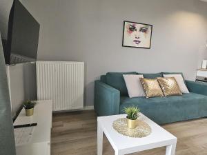 Urban Jungle - Space Apartment في بياويستوك: غرفة معيشة مع أريكة زرقاء وطاولة