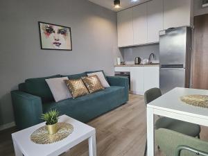 Urban Jungle - Space Apartment في بياويستوك: غرفة معيشة مع أريكة خضراء ومطبخ