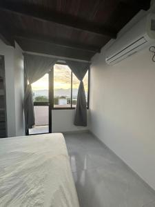a white bedroom with a bed and a window at Apartamento Bahía de Santa marta in Santa Marta