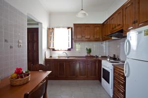 a kitchen with wooden cabinets and a table with a basket of fruit at Margarita Studios in Parikia