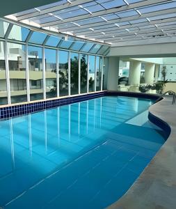 a large swimming pool in a building with glass windows at Flat ao lado do Mar Four Season in Guarujá