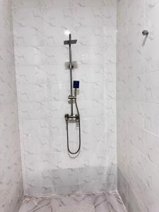 a shower in a white bathroom with a cross on the wall at Sunny Service Apartment in Lagos