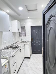 a kitchen with white cabinets and a black door at Sunny Service Apartment in Lagos