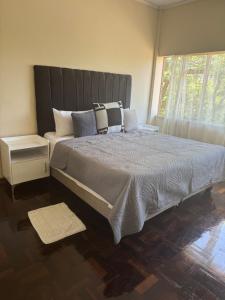 een slaapkamer met een groot bed met kussens en een raam bij Calenstel in Bulawayo