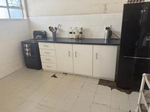 een keuken met witte kasten en een zwarte koelkast bij Calenstel in Bulawayo