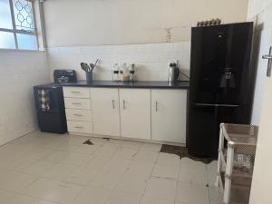 een keuken met een zwarte koelkast en witte kasten bij Calenstel in Bulawayo