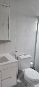 a white bathroom with a toilet and a sink at Apartamento 202 Bombinhas in Bombinhas