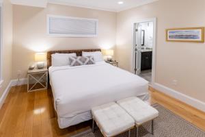 a bedroom with a large white bed and a stool at The Newport Lofts - 611 Thames Street in Newport