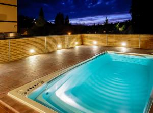 bañera de hidromasaje en una terraza por la noche con luces en Hotel Olberg, en Olomučany