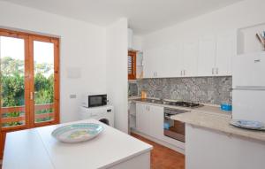 Una cocina con gabinetes blancos y un recipiente sobre una encimera. en Lovely Home In Santa Ma Del Focallo, en Pozzallo