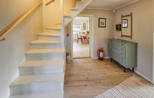 a staircase in a room with a dresser and a table at 3 Bedroom Cozy Home In Skjærhalden in Skjærhollen