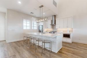 a kitchen with white cabinets and a island with bar stools at Sunrise Sunset Repeat in Port Aransas