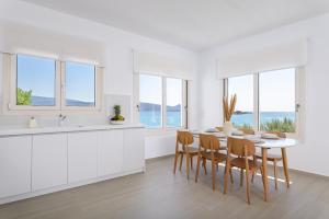 a white kitchen with a table and chairs and windows at BeachSide Escape Apartments in Psili Ammos
