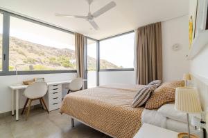 Un dormitorio con una cama, un escritorio y ventanas. en Exclusiva casa con encanto en Agua Amarga, en Agua Amarga