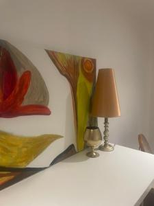 a table with a lamp and a painting on a wall at Gîte pieds dans l Epte prêt de Giverny in Gasny