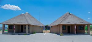 two buildings with thatched roofs in a parking lot at Kuswani Hotel in Sebina