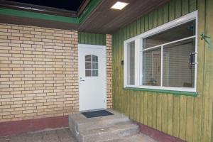 a green house with a white door and a window at Kent's Lodge in Herrefors
