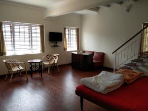 ein Wohnzimmer mit einem Bett, einem Tisch und Stühlen in der Unterkunft Colonels inn in Udagamandalam