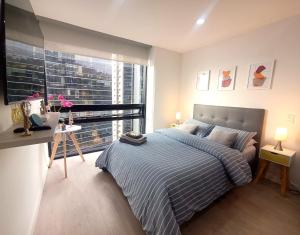 a bedroom with a bed and a large window at AH/Loft con Alexa, Parking, Coworking, Usaquén in Bogotá