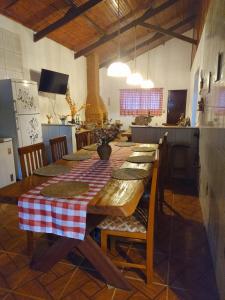 a kitchen with a wooden table with a red and white checkered table cloth at Recanto Sol Maior - Casa Girassol in Sapucaí-Mirim